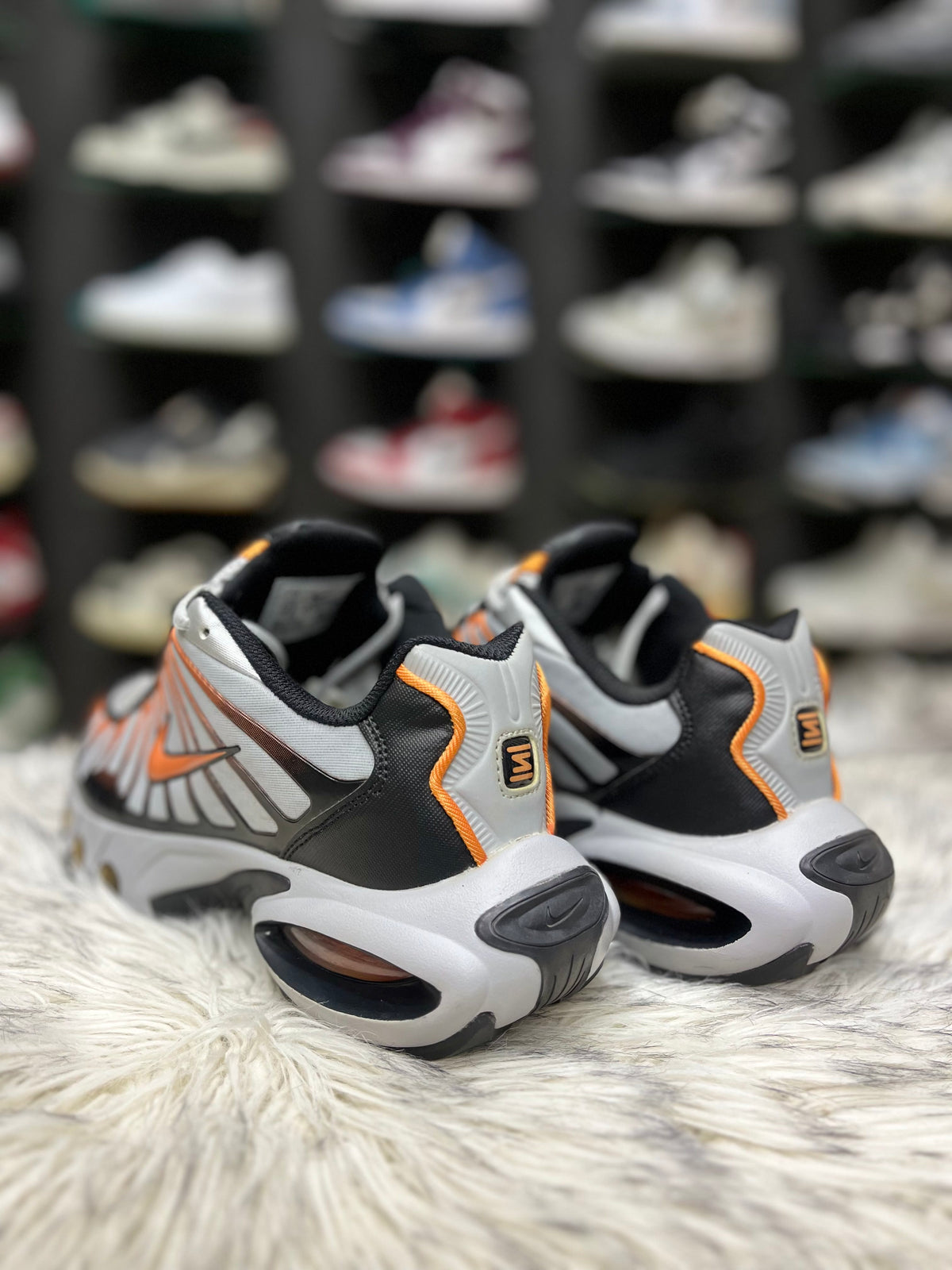 grey, black, and orange Nike Air Max Tailwind IV sneakers resting on a red Nike shoebox