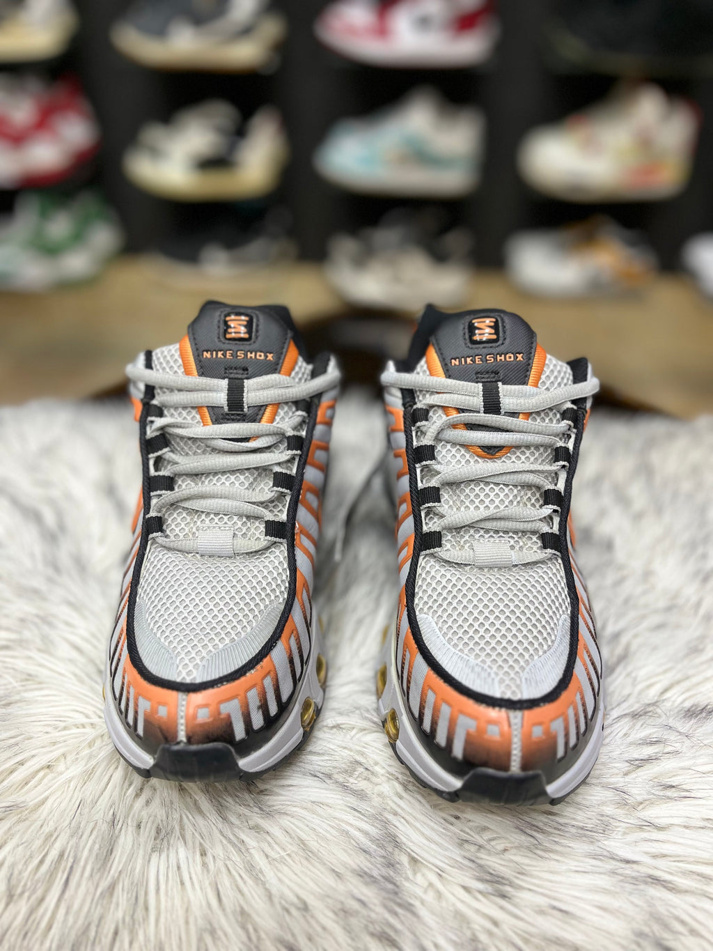 grey, black, and orange Nike Air Max Tailwind IV sneakers resting on a red Nike shoebox
